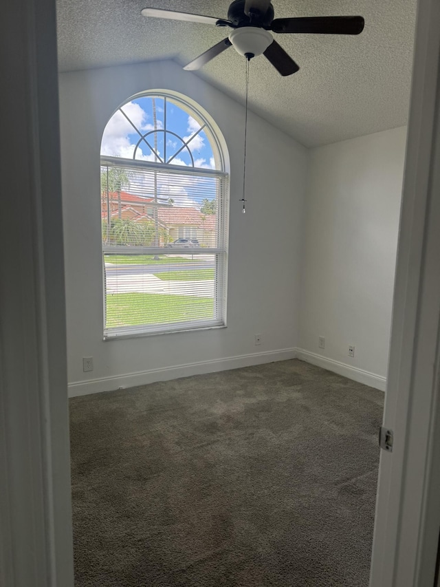 unfurnished room featuring ceiling fan, lofted ceiling, dark carpet, and a textured ceiling