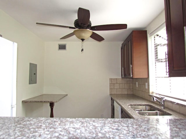 kitchen with tasteful backsplash, visible vents, electric panel, light stone counters, and a sink