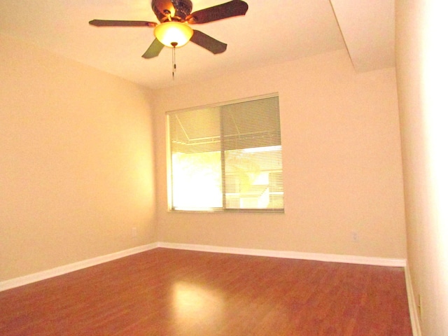 spare room featuring a ceiling fan, baseboards, and wood finished floors