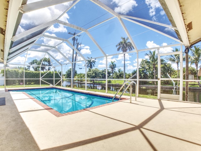 view of pool featuring a patio, a water view, and glass enclosure