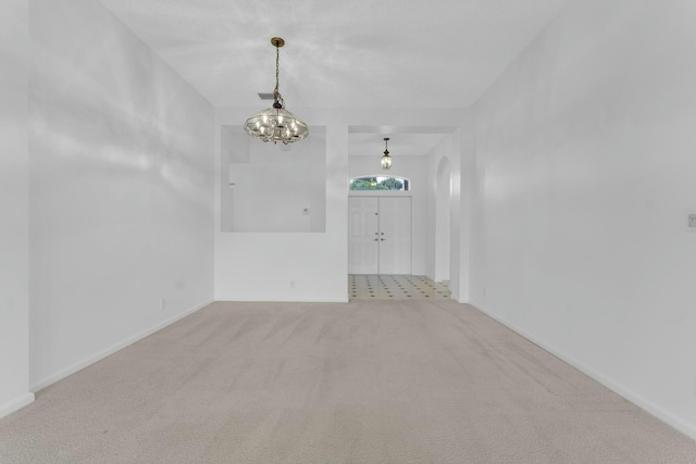 unfurnished room featuring light colored carpet and a notable chandelier