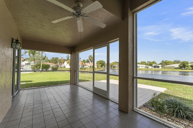 unfurnished sunroom with ceiling fan and a water view