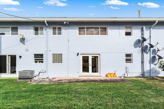 rear view of house featuring central AC unit, stucco siding, french doors, and a yard