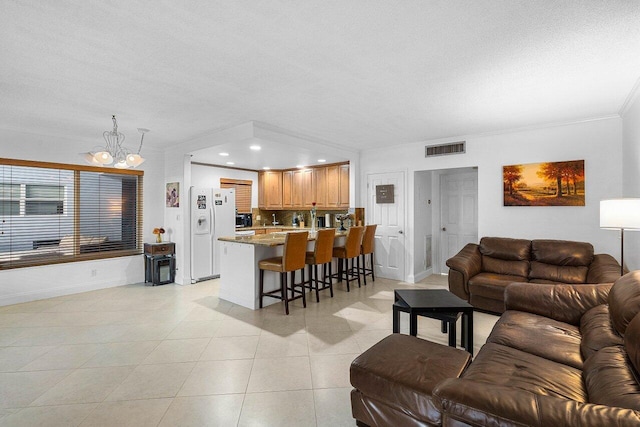 living room featuring visible vents, crown molding, baseboards, an inviting chandelier, and light tile patterned flooring