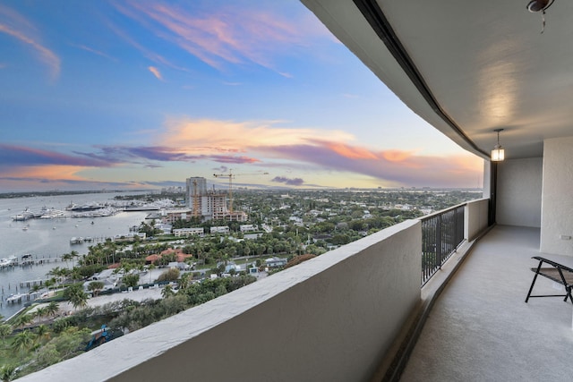 balcony at dusk featuring a water view