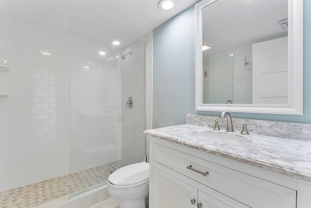 bathroom featuring vanity, toilet, and a tile shower