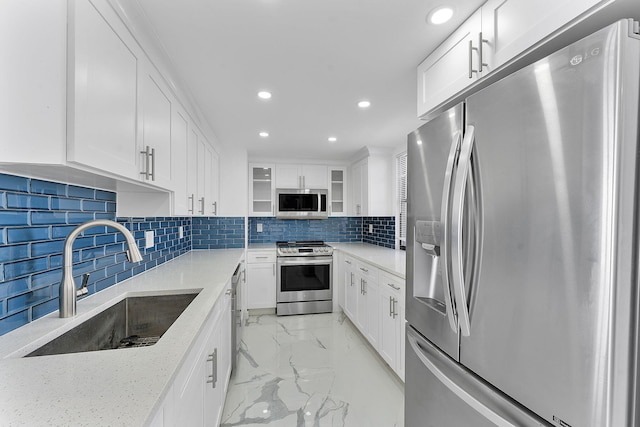 kitchen featuring white cabinetry, appliances with stainless steel finishes, light stone countertops, and sink