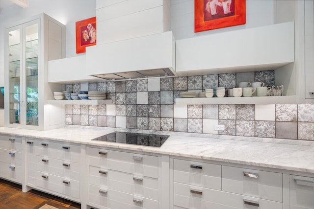 kitchen with black electric stovetop, decorative backsplash, custom exhaust hood, and light stone countertops