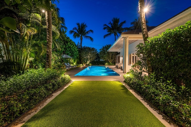 pool at twilight featuring a patio area and a lawn