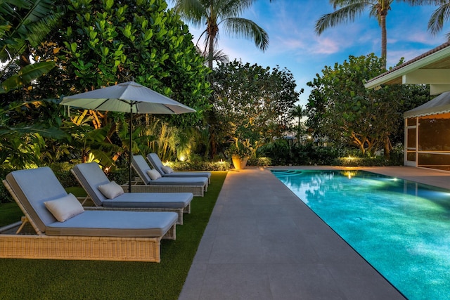 pool at dusk with a patio area