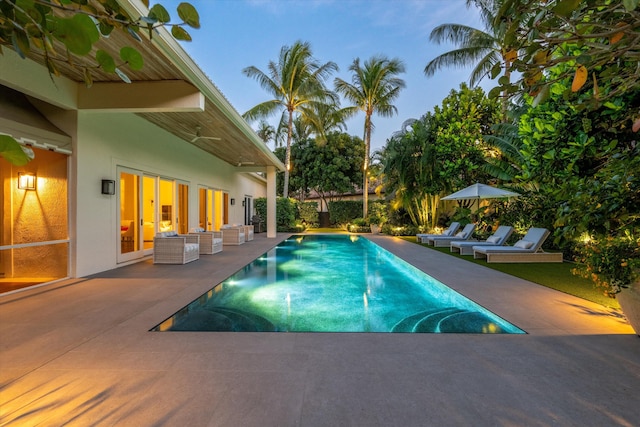 pool at dusk featuring a patio