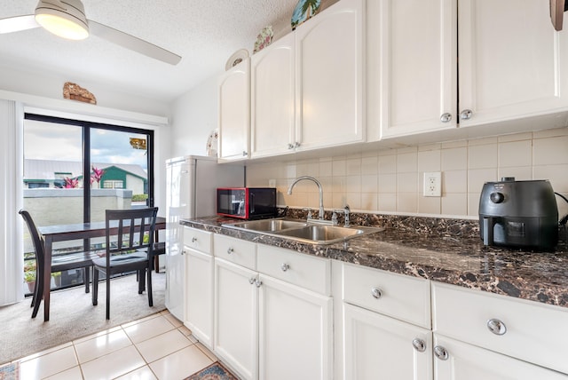 kitchen with sink, decorative backsplash, light tile patterned floors, and white cabinets