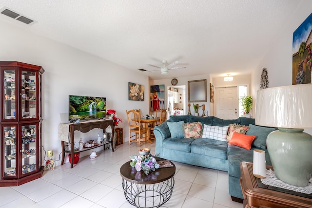 tiled living room featuring ceiling fan and a textured ceiling