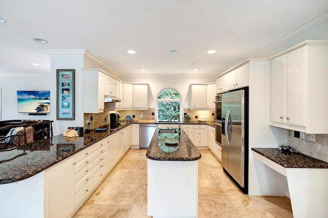 kitchen with stainless steel appliances, dark stone counters, and white cabinets