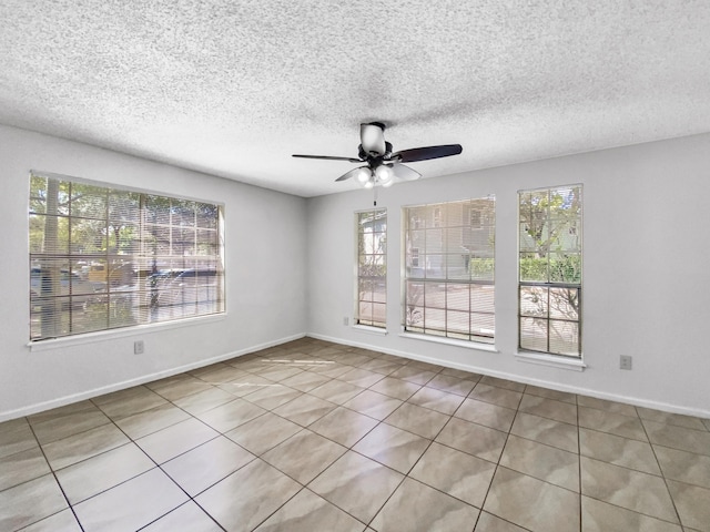 empty room with ceiling fan, a textured ceiling, and baseboards