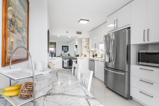 kitchen featuring stainless steel appliances, kitchen peninsula, decorative backsplash, and white cabinets