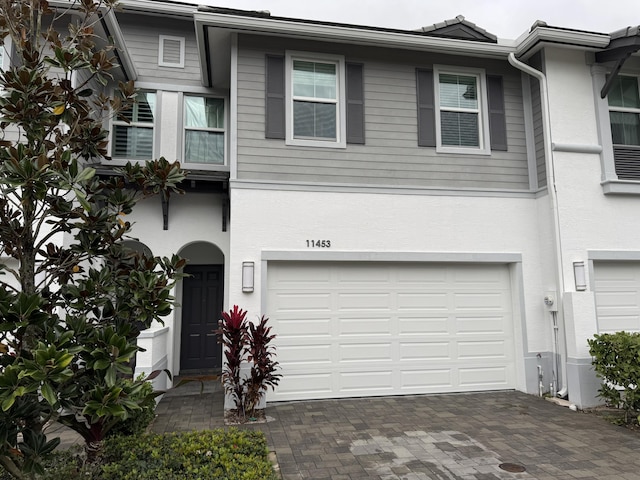 view of property with a garage, decorative driveway, and stucco siding