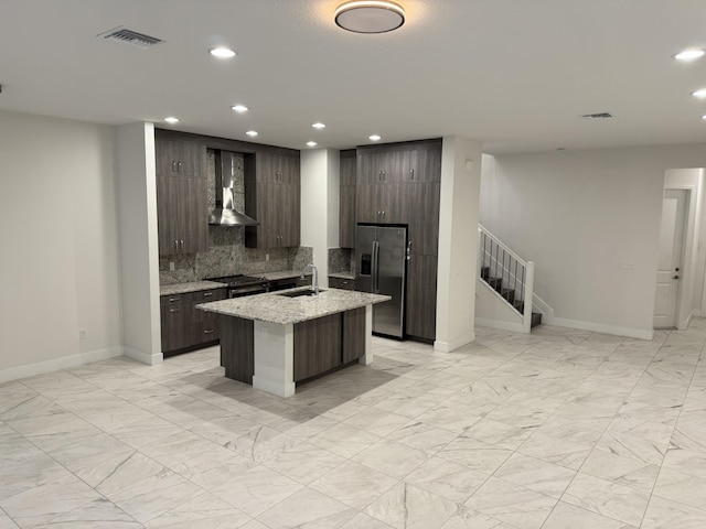 kitchen with a sink, visible vents, marble finish floor, wall chimney exhaust hood, and stainless steel fridge