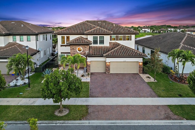 view of front of property with an attached garage, decorative driveway, a front yard, and a tile roof