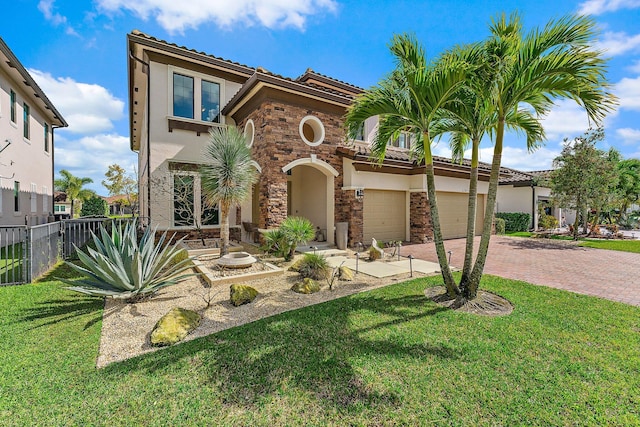 mediterranean / spanish home with fence, stone siding, decorative driveway, stucco siding, and a front lawn