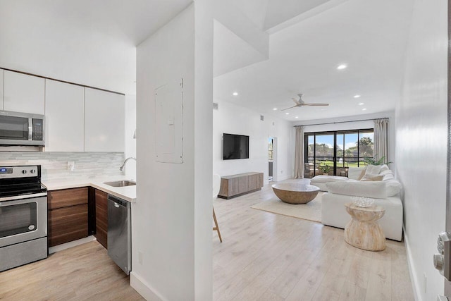 kitchen with stainless steel appliances, white cabinetry, tasteful backsplash, and light hardwood / wood-style floors