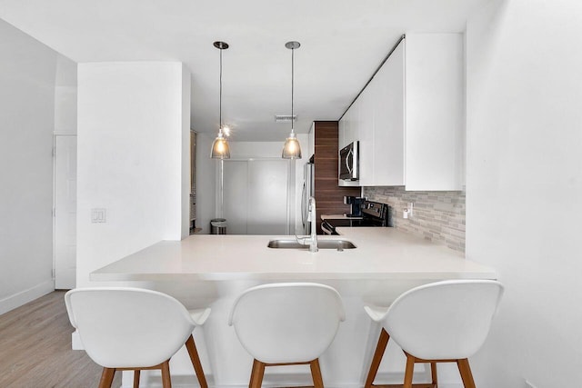 kitchen featuring electric range oven, pendant lighting, decorative backsplash, and kitchen peninsula