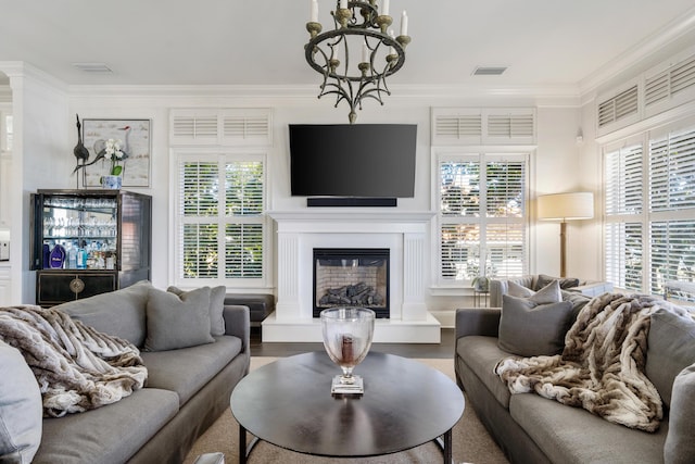 living room featuring ornamental molding, a healthy amount of sunlight, and an inviting chandelier