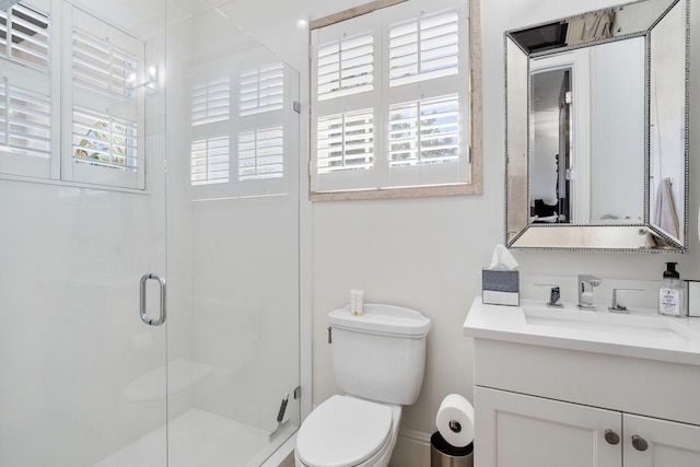 bathroom featuring a shower with door, vanity, and toilet