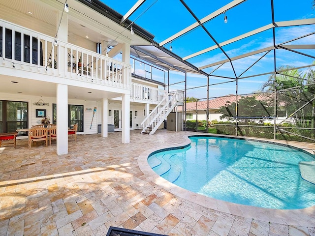 view of swimming pool featuring a patio and glass enclosure