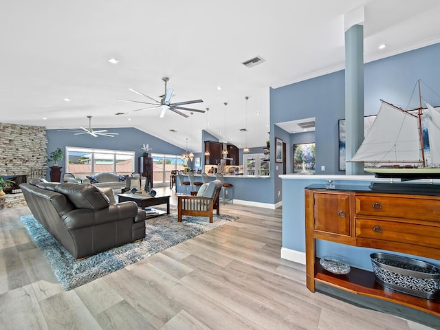 living room with light hardwood / wood-style floors, vaulted ceiling, ceiling fan, and a fireplace