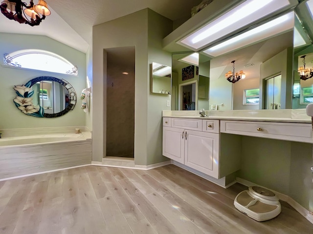 bathroom featuring lofted ceiling, an inviting chandelier, hardwood / wood-style floors, vanity, and shower with separate bathtub