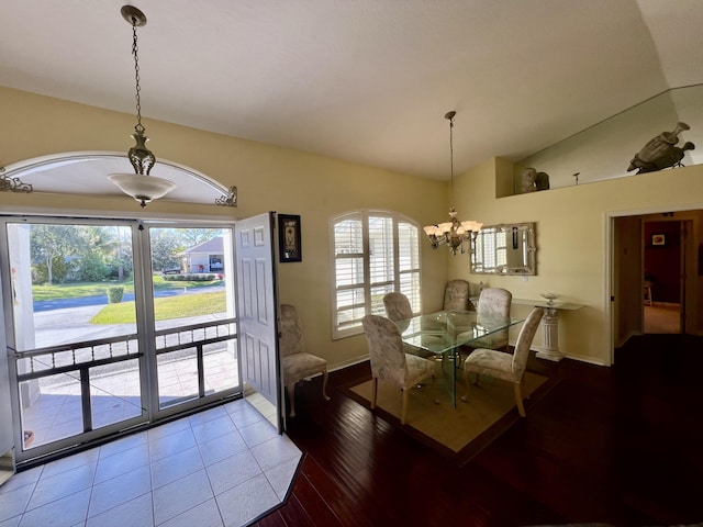 dining room with an inviting chandelier, hardwood / wood-style floors, and vaulted ceiling