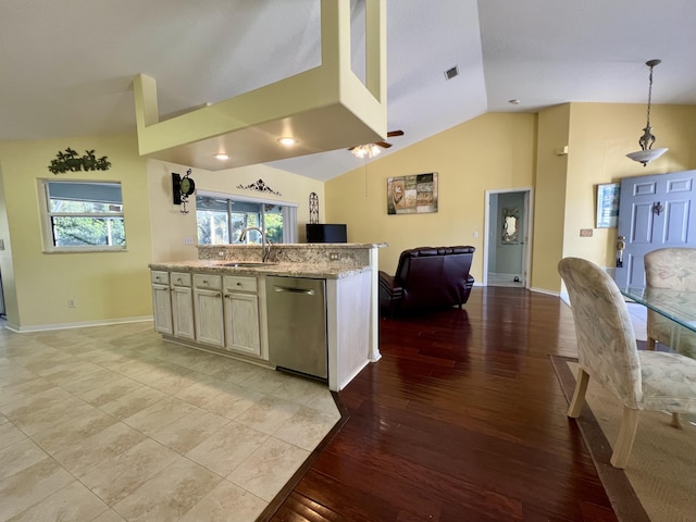 kitchen featuring sink, vaulted ceiling, stainless steel dishwasher, pendant lighting, and light stone countertops