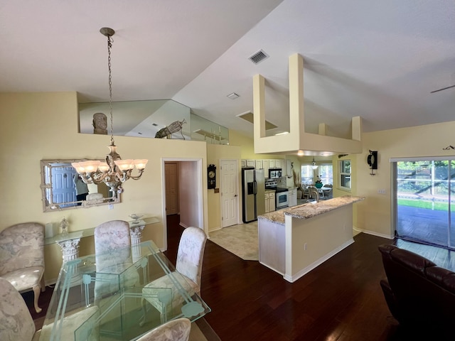 dining area with lofted ceiling, hardwood / wood-style floors, and an inviting chandelier