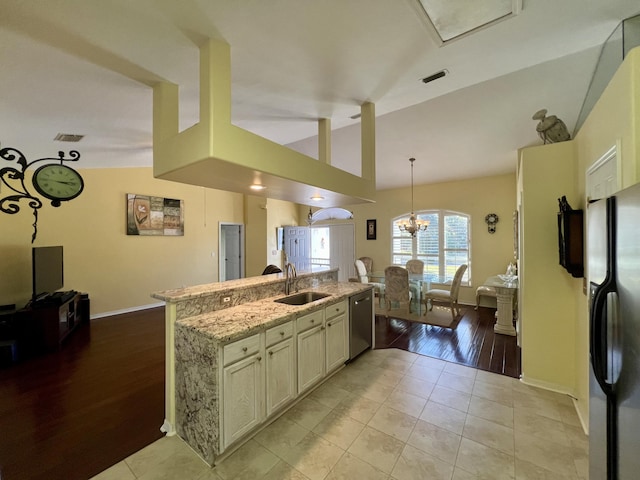 kitchen featuring vaulted ceiling, sink, light tile patterned floors, stainless steel appliances, and light stone countertops