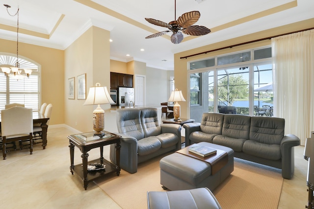 tiled living room with ornamental molding, ceiling fan with notable chandelier, and a tray ceiling