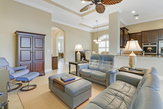 tiled living room with a tray ceiling, sink, ceiling fan with notable chandelier, and ornamental molding