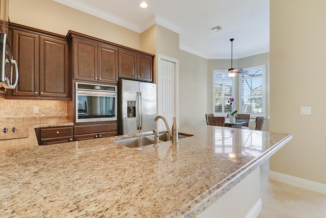 kitchen with sink, decorative backsplash, ornamental molding, stainless steel appliances, and light stone countertops