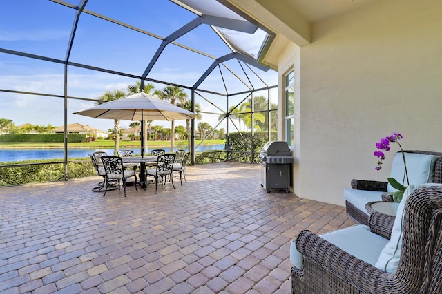 view of patio with a water view, grilling area, outdoor lounge area, and glass enclosure