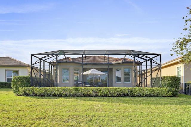 back of property featuring a yard and glass enclosure