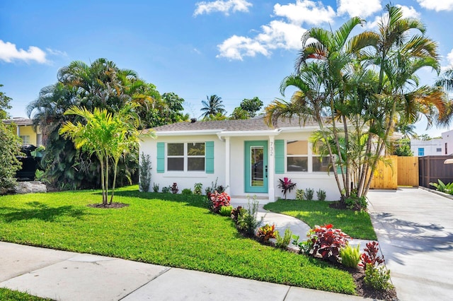 ranch-style home featuring driveway, stucco siding, fence, and a front yard