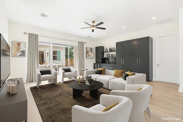 living room with light wood-type flooring, a ceiling fan, visible vents, and recessed lighting