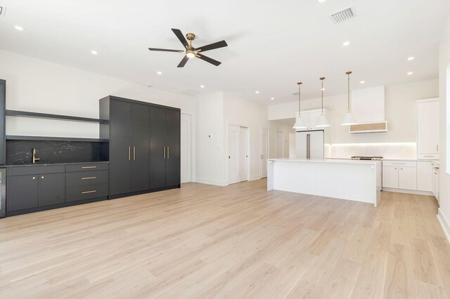 kitchen with light wood-style floors, range hood, ceiling fan, a kitchen island, and built in fridge