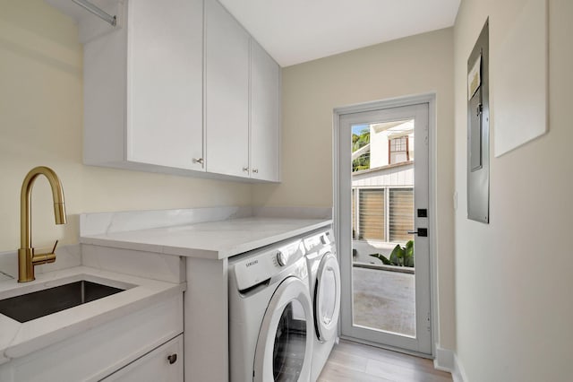 clothes washing area featuring cabinet space, light wood-type flooring, separate washer and dryer, and a sink