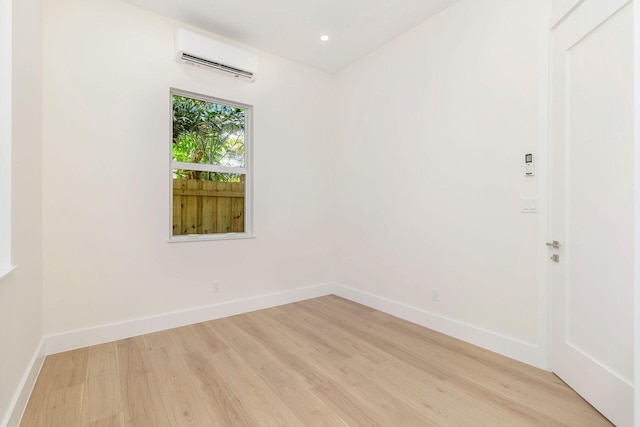 empty room featuring a wall mounted air conditioner, recessed lighting, light wood finished floors, and baseboards
