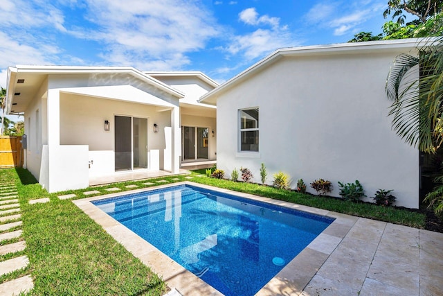 rear view of property with a yard, an outdoor pool, a patio, and stucco siding