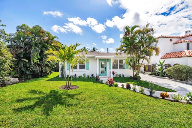 mediterranean / spanish-style home featuring concrete driveway, stucco siding, and a front lawn