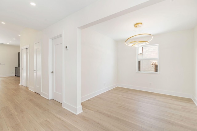 spare room with light wood finished floors, baseboards, a notable chandelier, and recessed lighting