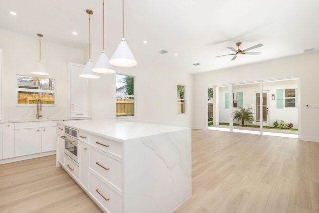 kitchen featuring light wood-type flooring, a sink, oven, and a ceiling fan