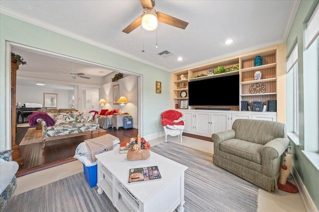 living room with built in shelves, ornamental molding, and ceiling fan